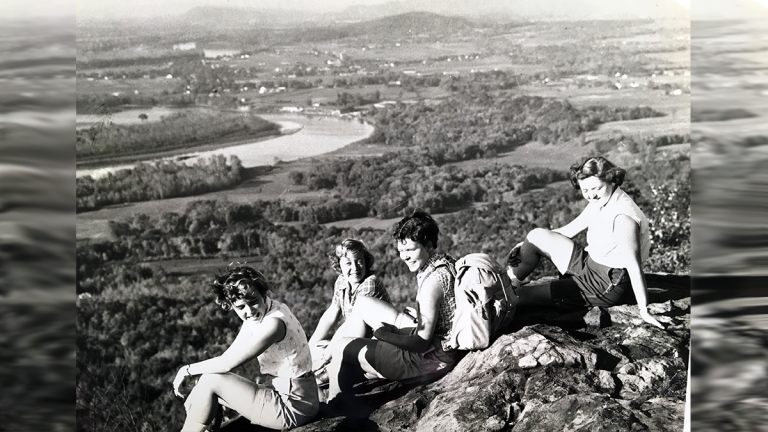 Four students enjoying the view of the Connecicut River from atop Mount Holyoke on Mountain Day 1955.