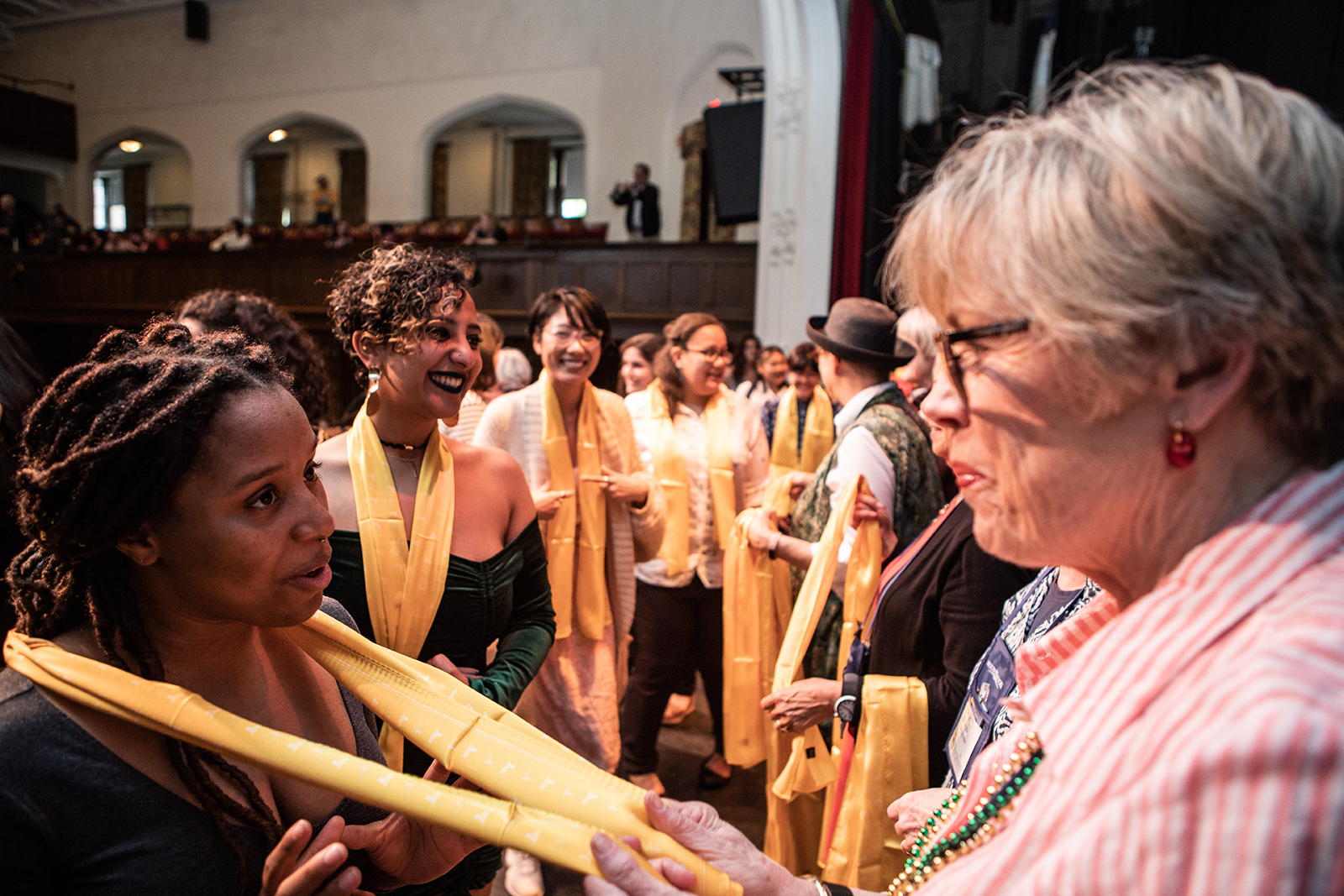 An alum presenting a scarf to a graduating senior in their class color
