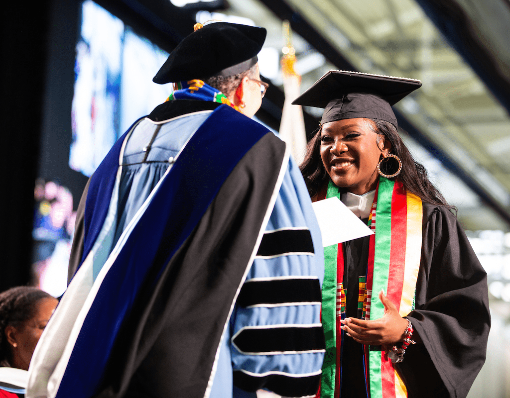 Interim President Beverly Danial Tatum presents a diploma to a student during Commencement 2023