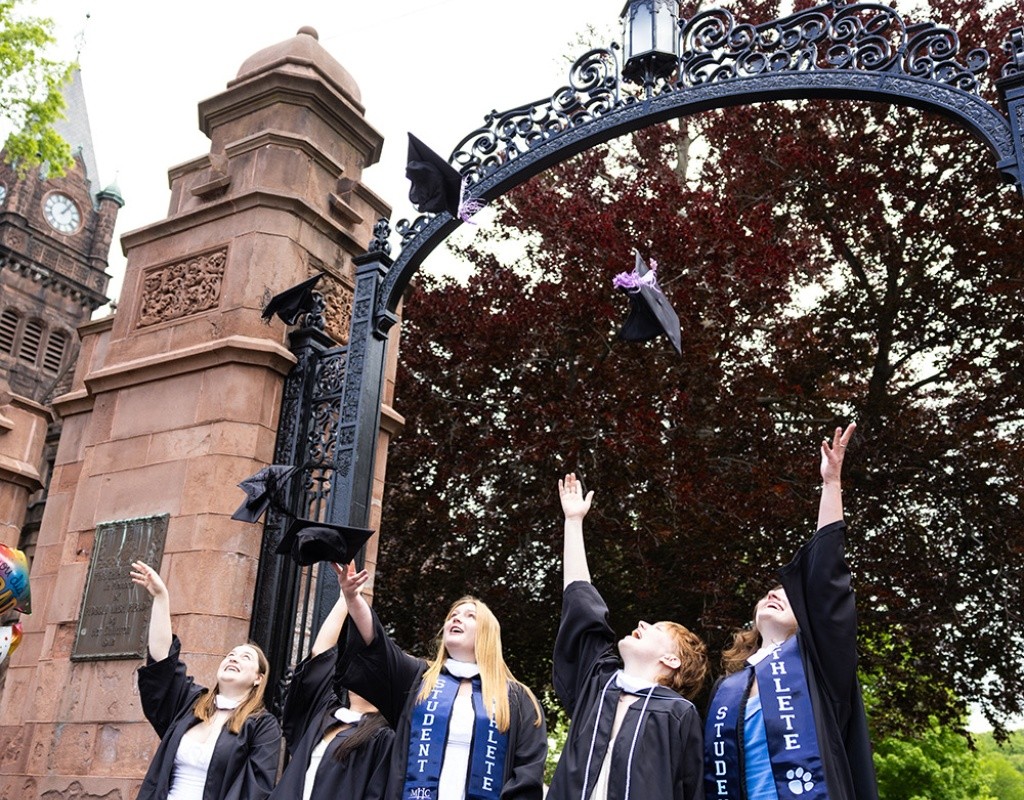 Mount Holyoke Commencement 2024 - Graduating students toss their caps in the air in front of the gates