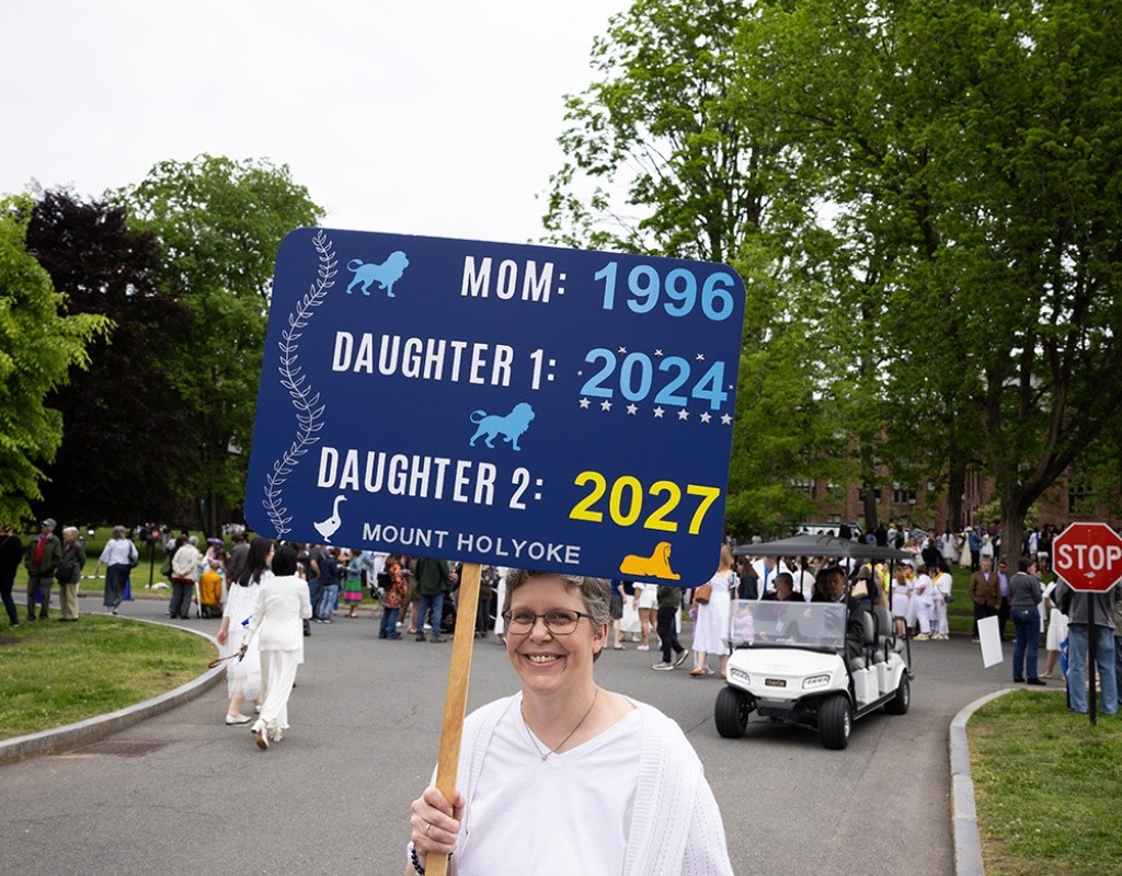 Mount Holyoke Commencement 2024 - An alum holds a sign with dates their family has graduated from Mount Holyoke