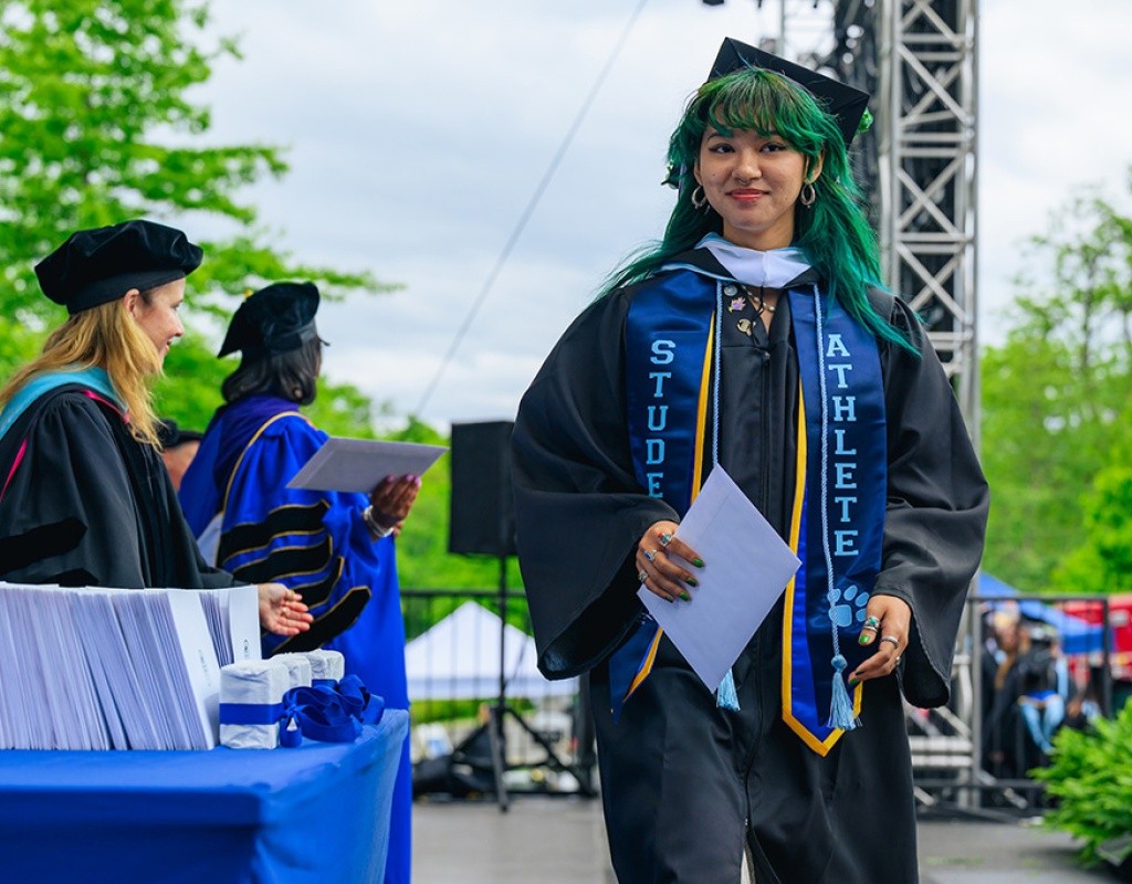Student walks across the stage to collect their diploma.