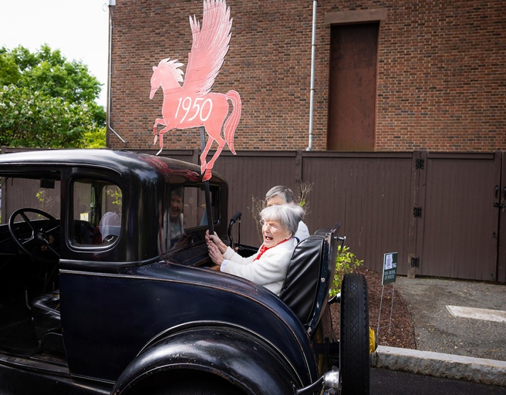 Laurel parade participant waves from the back of an old-fashioned car.