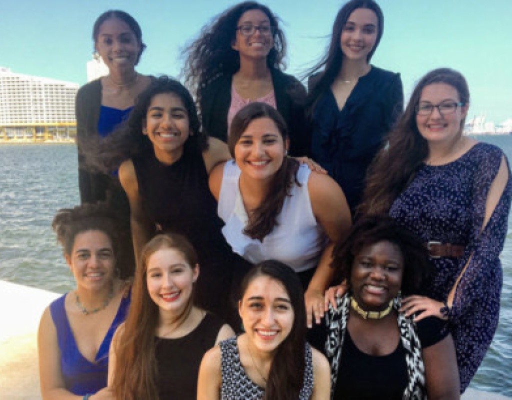 Posse scholars pose clustered together, the ocean behind them.