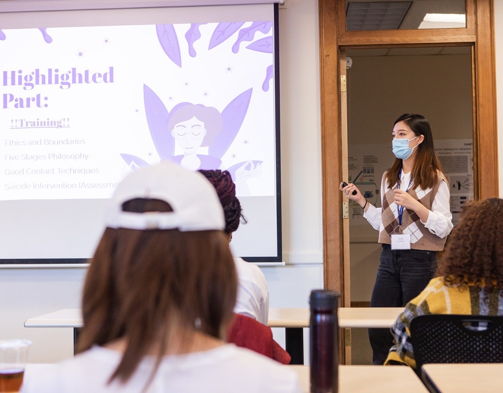 A student standing next to a presentation screen while giving a presentation during LEAP Symposium 2022