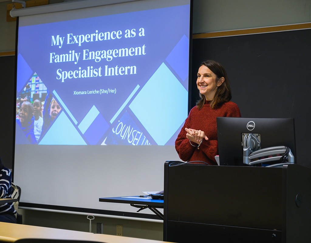 Student standing in front of a presentation screen. LEAP 2024, Mount Holyoke College