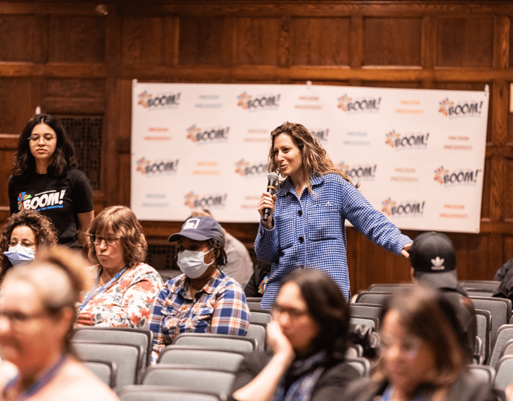 Two members of the audience standing to ask questions during the 2023 Boom! Learning Symposium