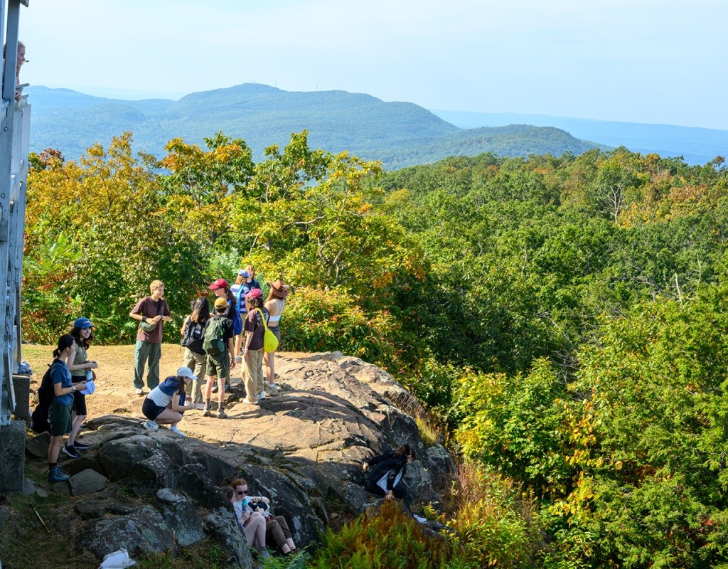 Mountain Day 2024 - Students climbing the mountain and standing on the rock to take photos of the valley.
