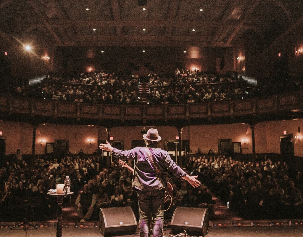 Interior of Academy of Music in Northampton.  Photo taken from behind a performer on stage with a view of the audience.