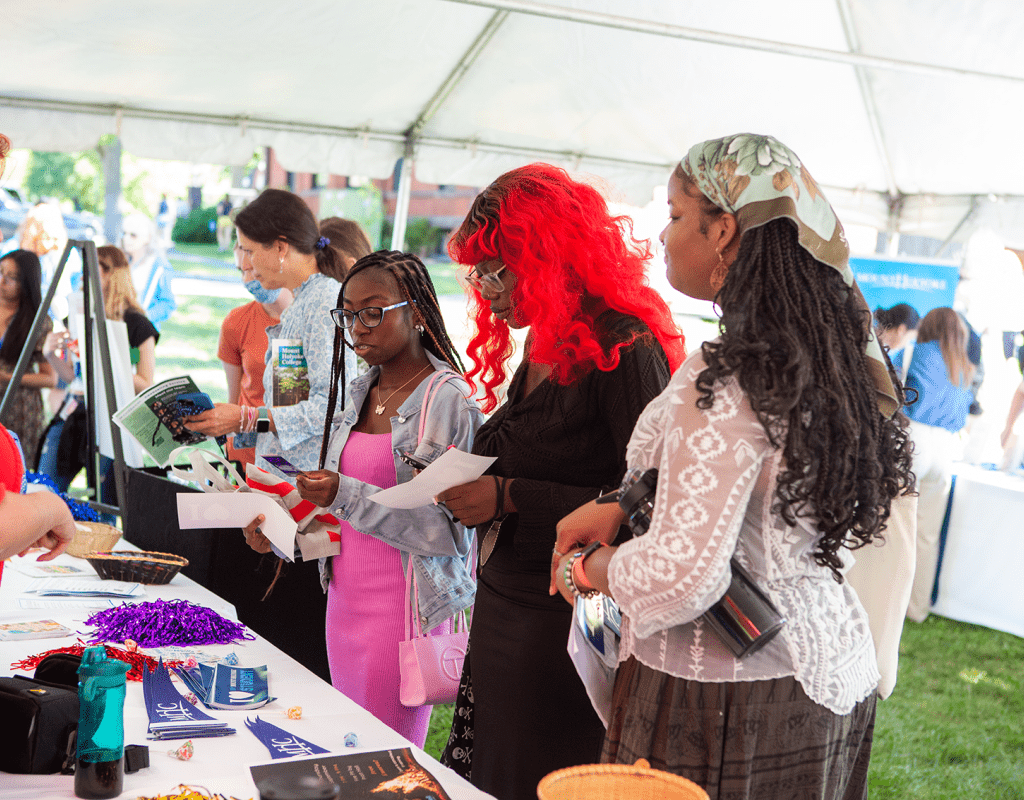 Students asking questions at an information table in the welcome tent during move-in day 2022