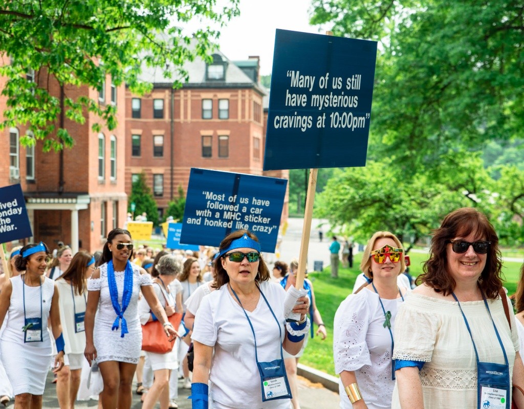 A blue pegasus class marches in the Laurel Parade, one of whom is holding a sign that says &quot;Many of us still have mysterious cravings at 10pm&quot;