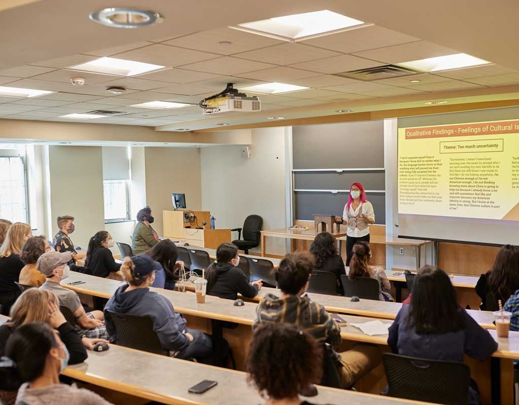 A student presenting in front of a lecture hall during Senior Symposium