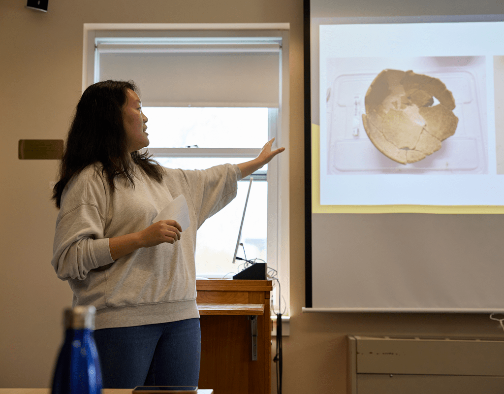 A student jestering at the projector screen while giving their presentation during Senior Symposium 2023