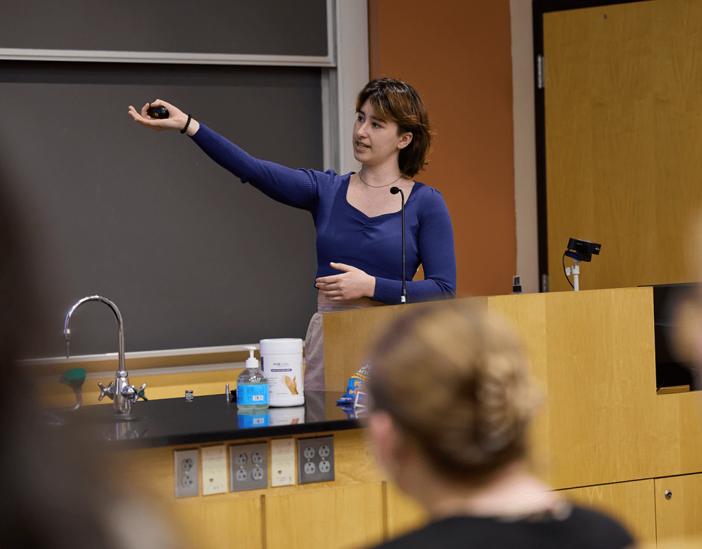 A student jestering at the blackboard during Senior Symposium 2023