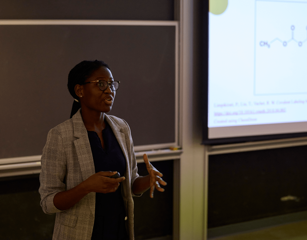 Black student with glasses wearing a jacket presents at symposium 2023.