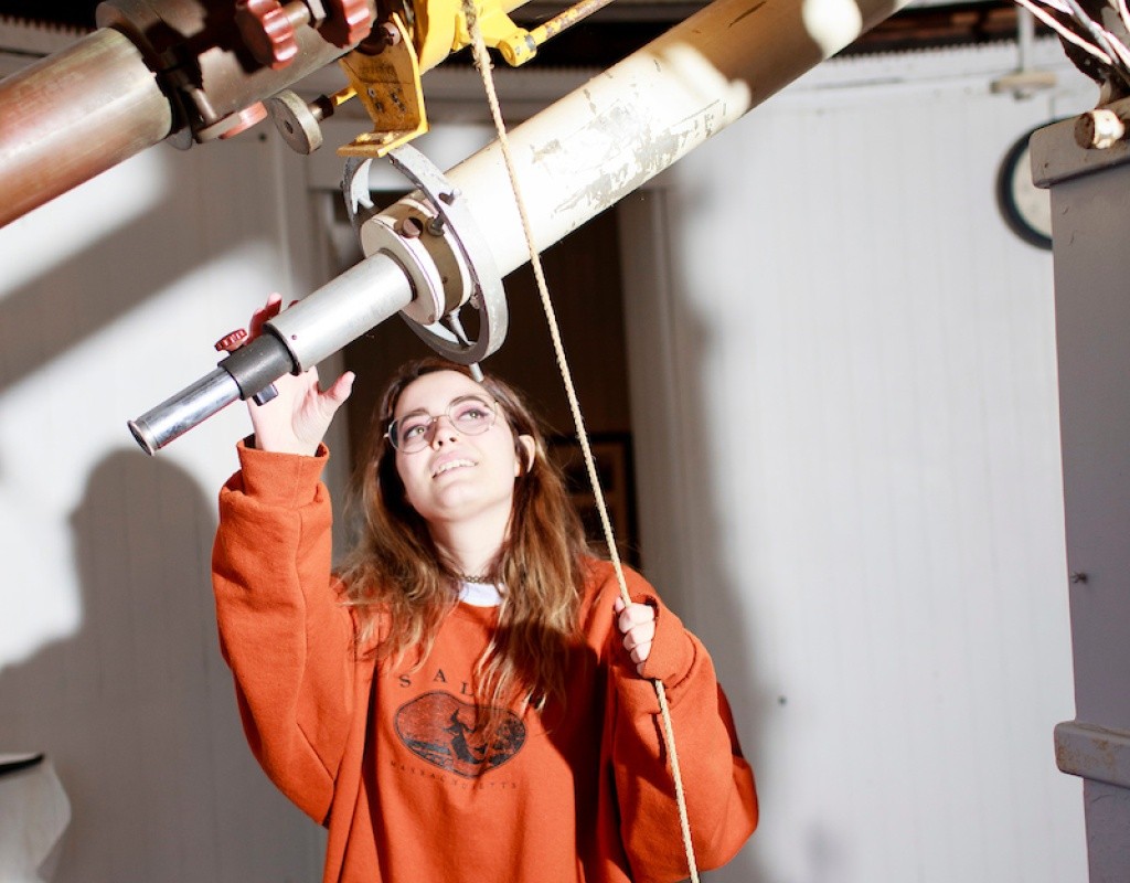 A student poses with the telescope in the obseervatory