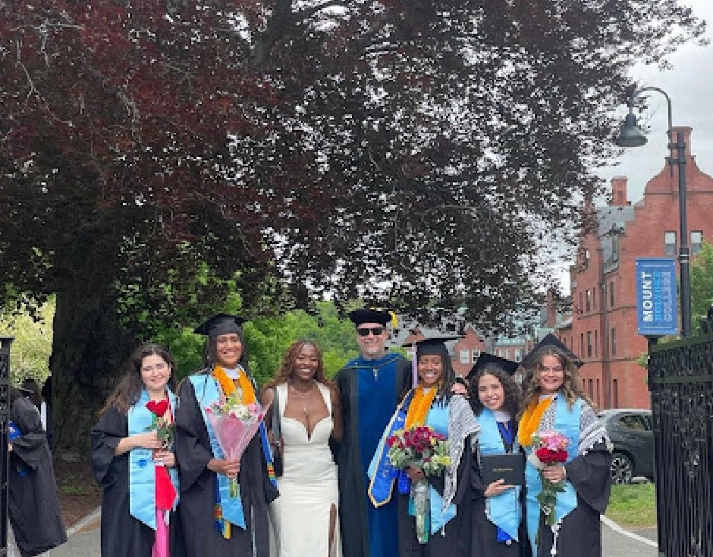 Posse scholars pose in regalia, some holding flowers.