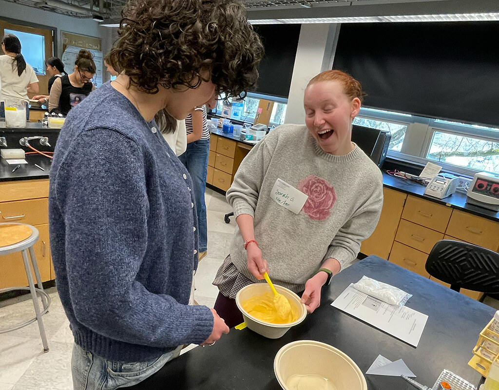 QIC students mix their yellow slime ingredients together.