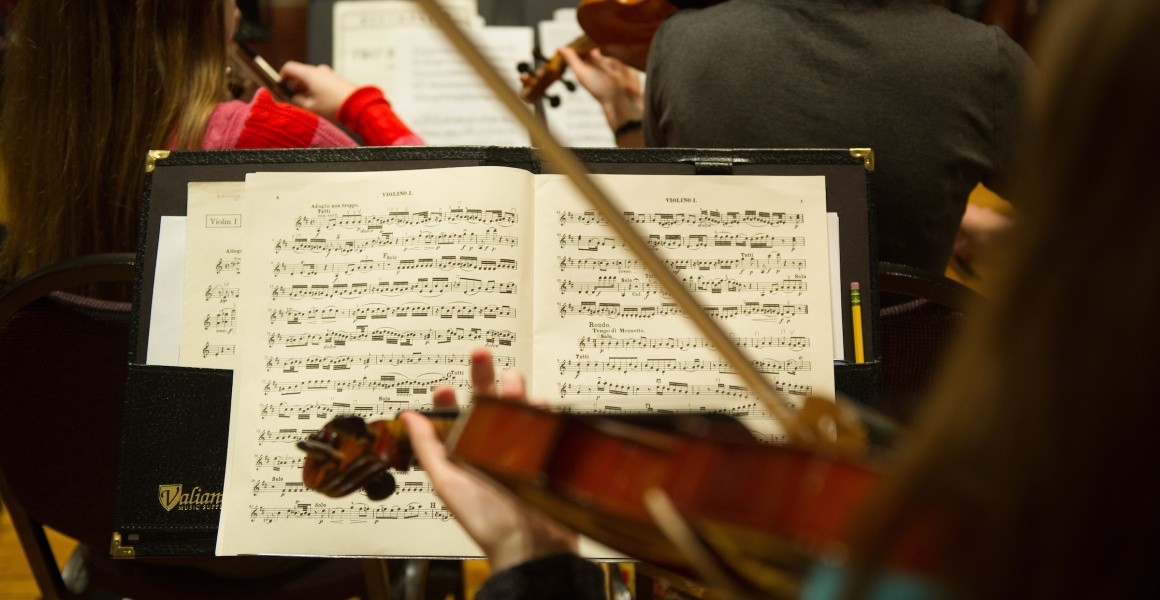 A piece of music on a music stand in front of a student playing the violin