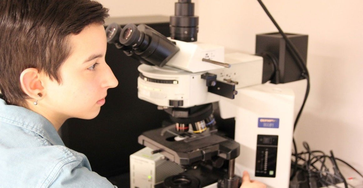 Mount Holyoke College student looking through microscope