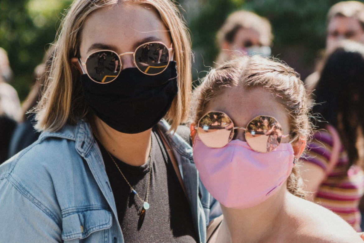 Two students pose together wearing masks.