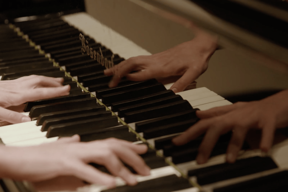 A close-up of a student's hands playing the piano