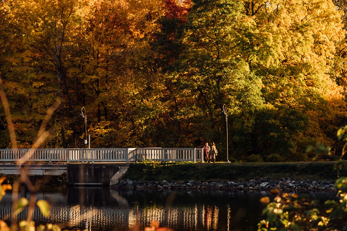 Students crossing the Lower Pond bridge in fall.
