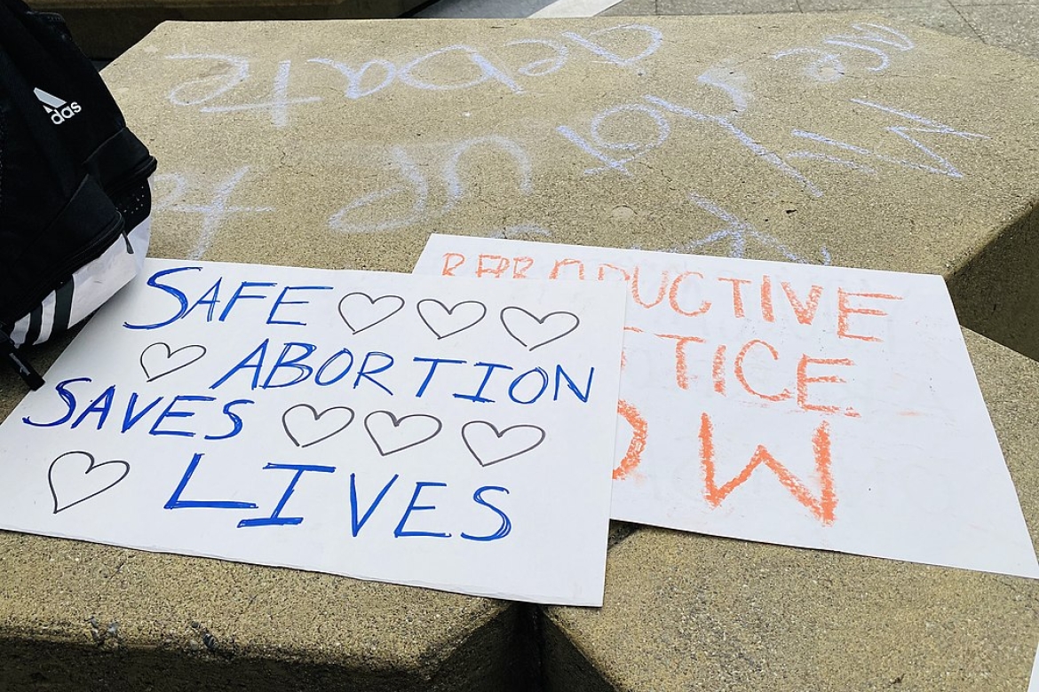 Rally signs lying on a sidewalk: "Save Abortion. Save Lives", "Reproductive Justice Now"