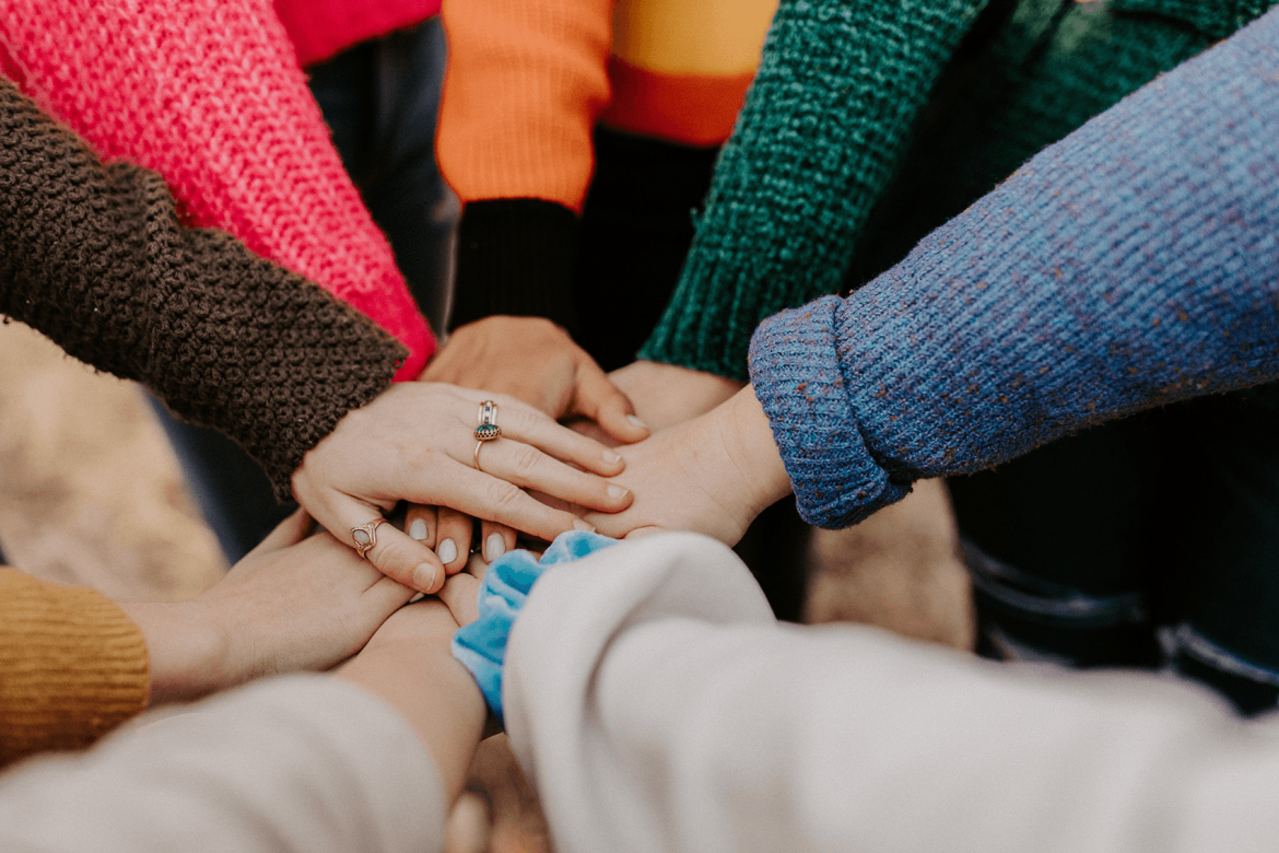 A group of people holding their hands together in a circle