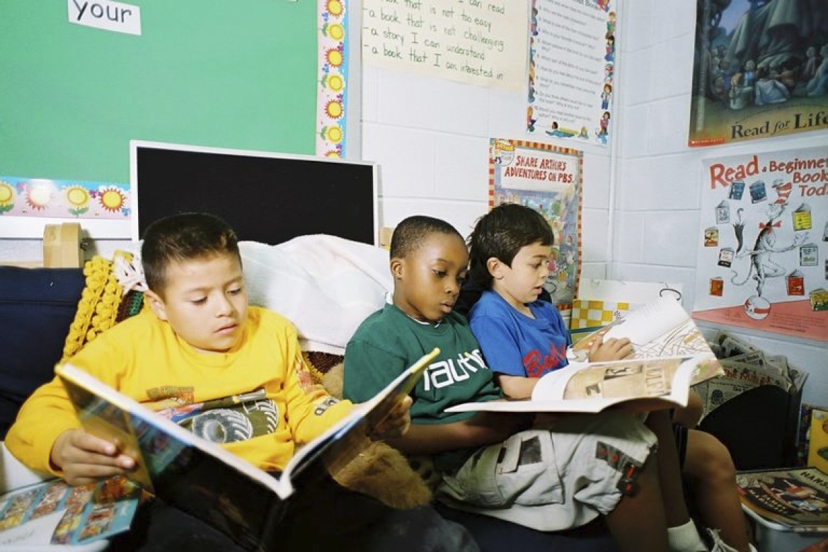 Three primary school children reading in a classroom