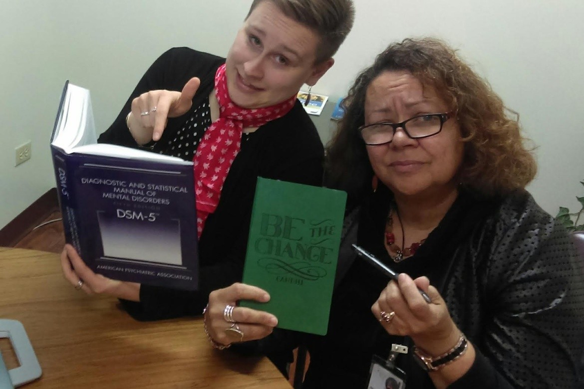 Megan Brookman with her supervisor holding a “Be the Change” sign. Image courtesy of Megan Brookman ‘14.