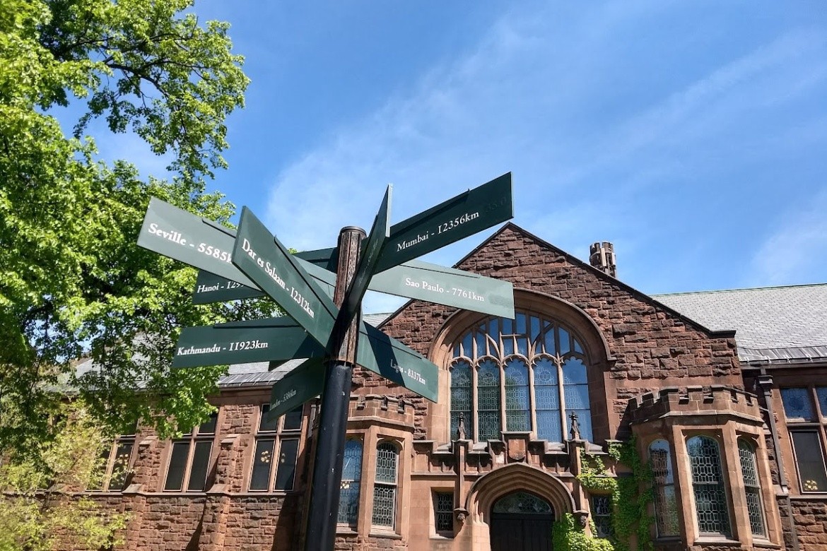 Directional sign on campus pointing to various international cities and their distance from campus.