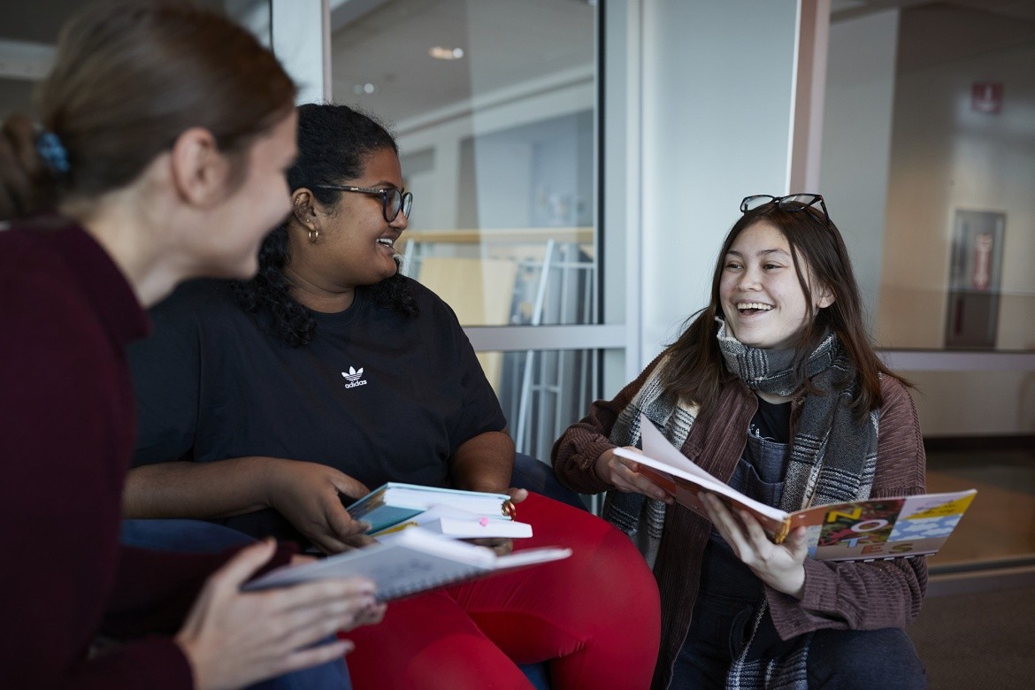 Students sat together, smiling, holding books.