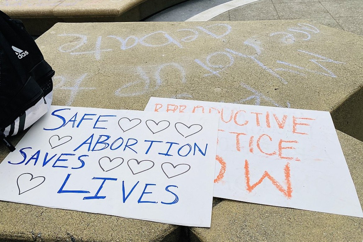 Rally signs lying on a sidewalk: "Save Abortion. Save Lives", "Reproductive Justice Now"