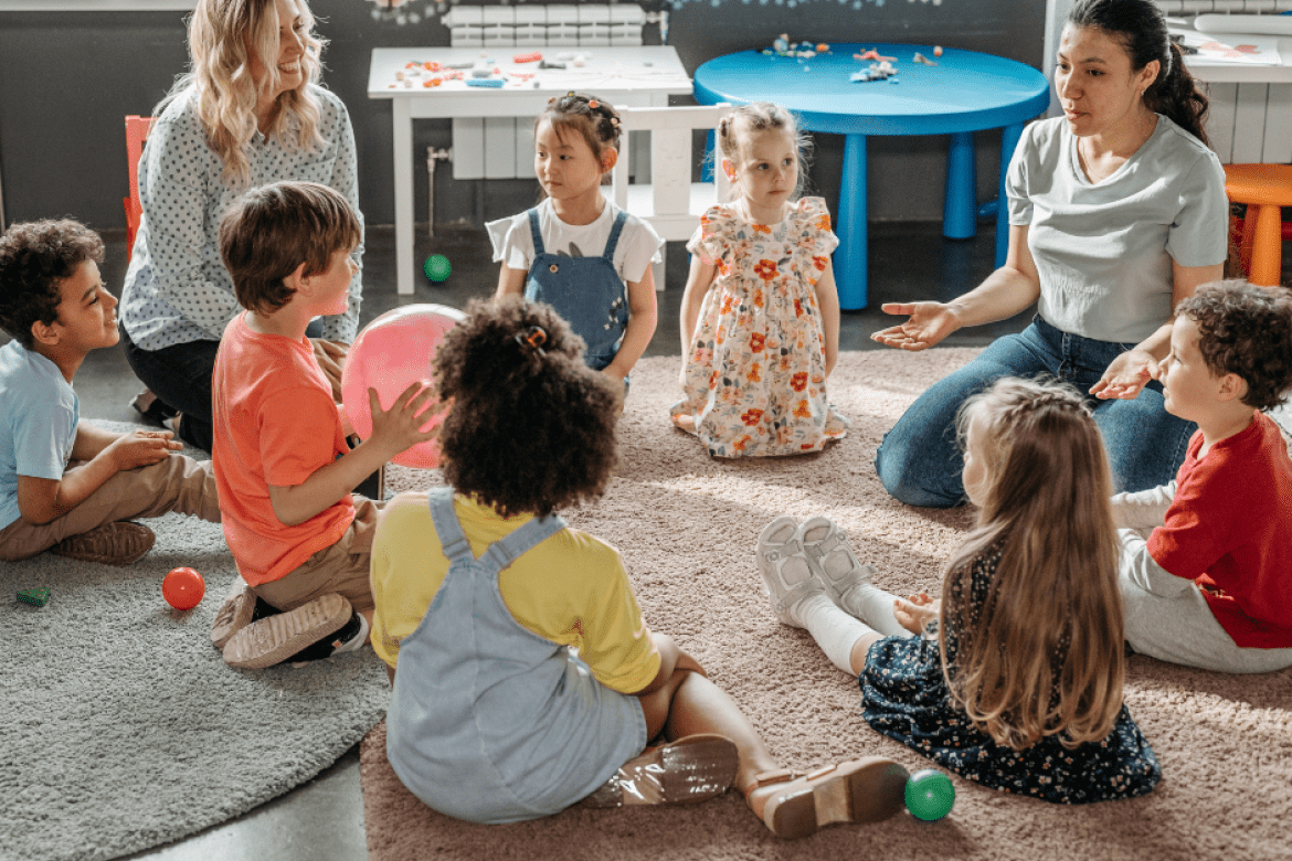 Young students sitting in a circle with teachers.
