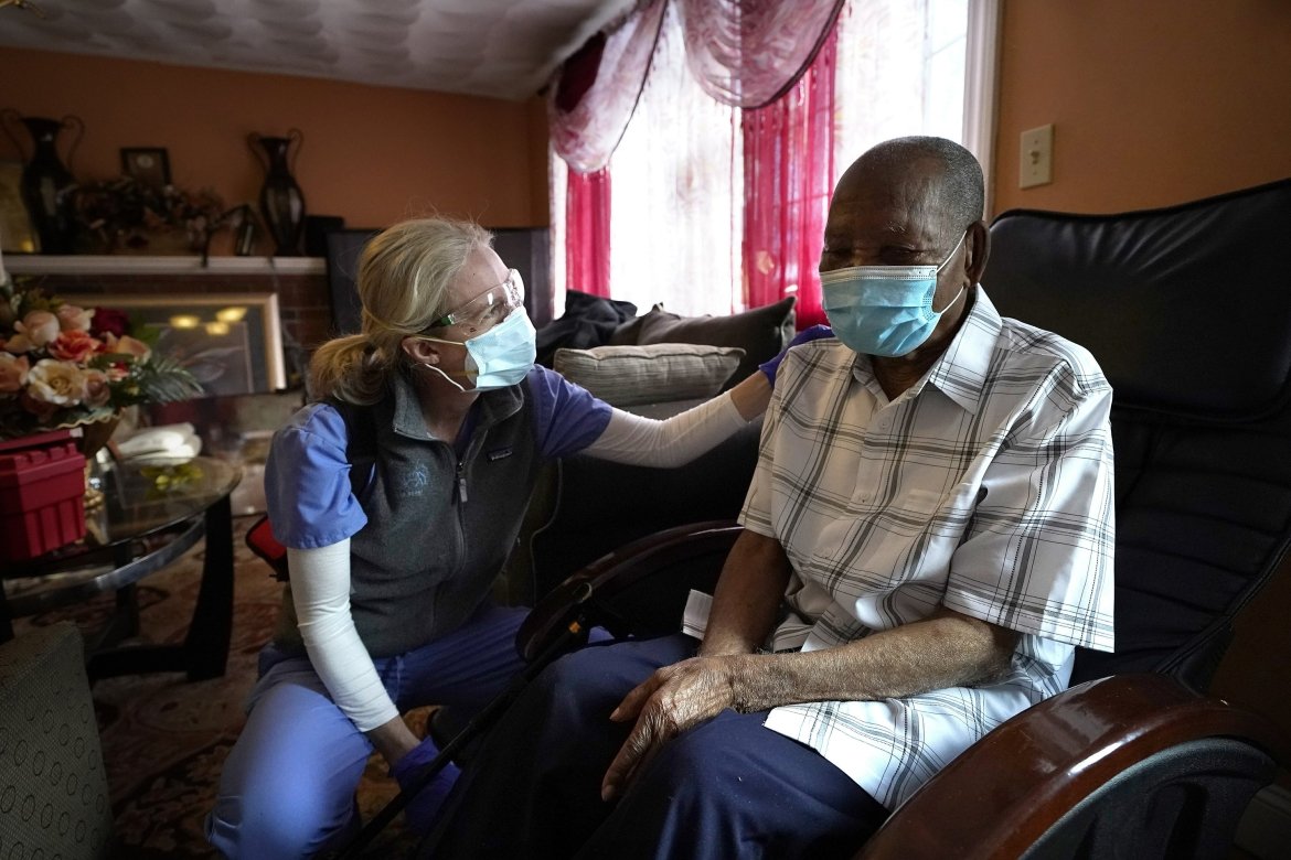 Alum Dr. Megan Young, left, offers support to Edouard Joseph, 91, moments after giving him a COVID-19 vaccination, Thursday, Feb. 11, 2021, at his home in the Mattapan neighborhood of Boston. (Photo courtesy of AP)