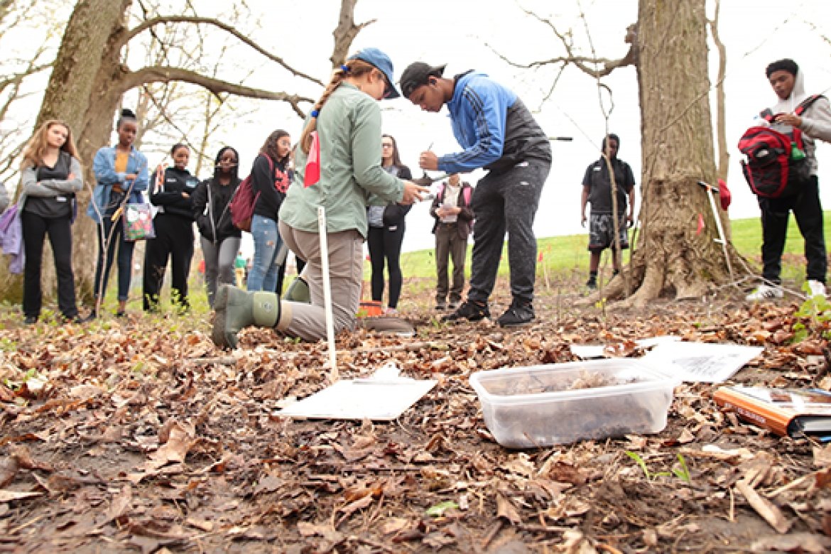 Kate Ballantine with a group of students examining a soil sample on the Project Stream site.