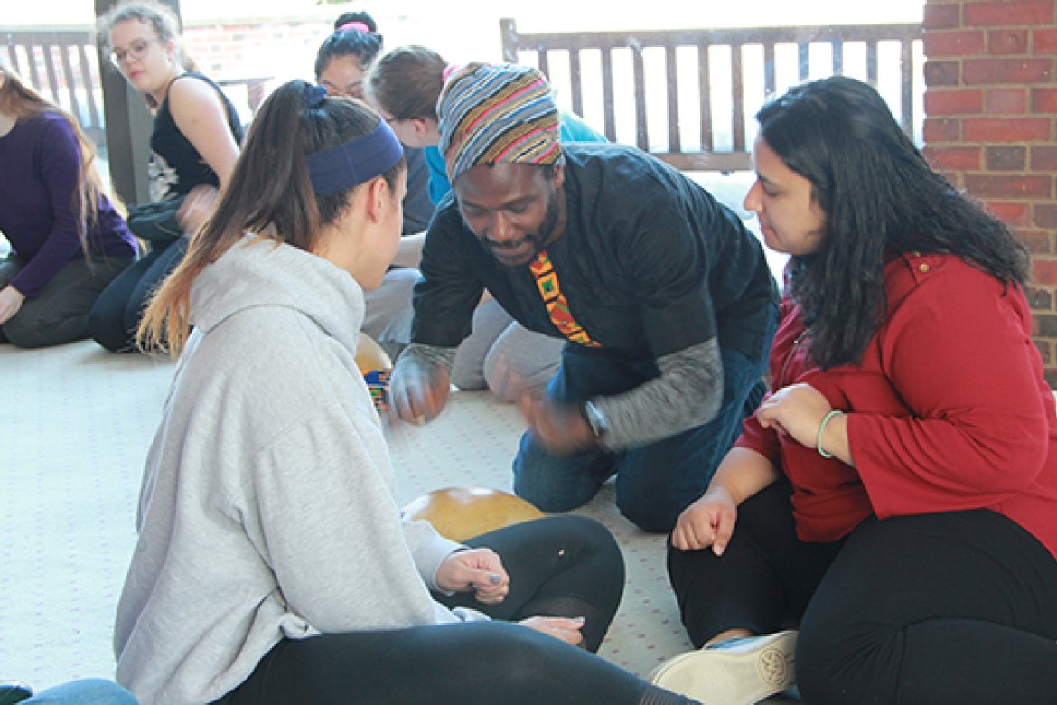 Guest artist Mohammed Alidu, center, demonstrates a rhythm on the calabash to students.