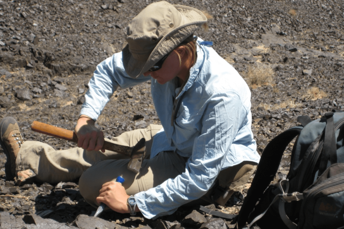 Rita C. Economos ’01 chiseling rock in the field.