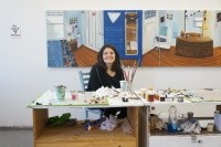 Anna Berlin ’15 sitting at a desk surrounded by art.