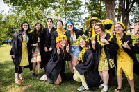 A group of seniors in their graduation robes with yellow clothing underneath ready for Convocation 2022