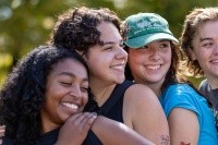 Four friends - Mount Holyoke students - pose for a photo at the top of Mt. Holyoke on Mountain Day, 2025. Photo by Max Wilhelm.
