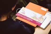 A look over a student's shoulder, laptop and flyer in view, it reads: Challenge your worldview. Chart your global path.