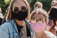 Two students pose together wearing masks.