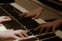 A close-up of a student's hands playing the piano