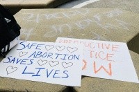 Rally signs lying on a sidewalk: &quot;Save Abortion. Save Lives&quot;, &quot;Reproductive Justice Now&quot;