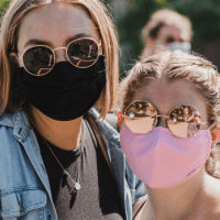 Two students pose together wearing masks.
