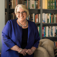 Sonya Stephens standing by a window, a book case behind her.