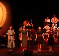 big-broadcast-group-singing.jpeg Four students singing on stage during a performance of the Big Broadcast