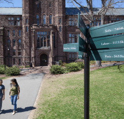 Aerial photo of two students walking near the library with the international signpost in the foreground